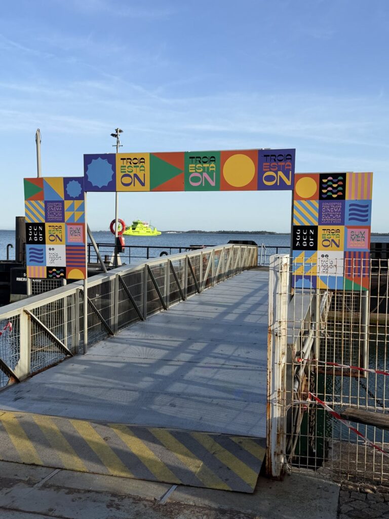 Pórtico colorido Troia Está On no passadiço da marina